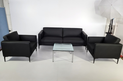 Sitzgruppe mit einem schwarzen Sofa, zwei Sessel und einem Glastisch