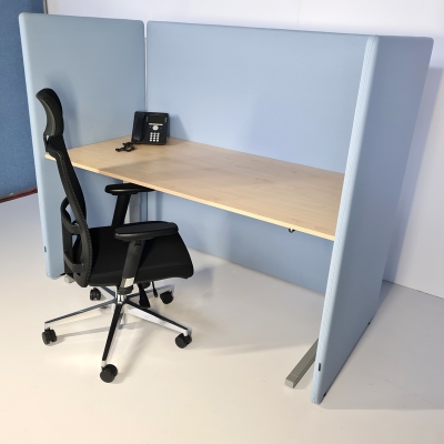 Arbeitsplatz mit Schreibtisch und hellblauer Trennwand als Einhausung