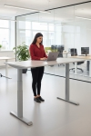 Frau an einem Steh-Sitz-Schreibtisch in einem Büro mit Laptop