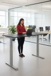 Frau an einem Steh-Sitz-Schreibtisch in einem Büro mit Laptop