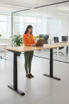 Frau an einem Steh-Sitz-Schreibtisch in einem Büro mit Laptop