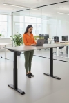 Frau an einem Steh-Sitz-Schreibtisch in einem Büro mit Laptop