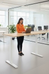 Frau an einem Steh-Sitz-Schreibtisch in einem Büro mit Laptop